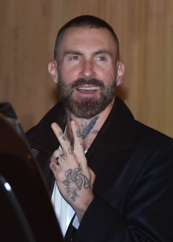 Adam Levine faz gesto para fotógrafos antes de entrar no carro