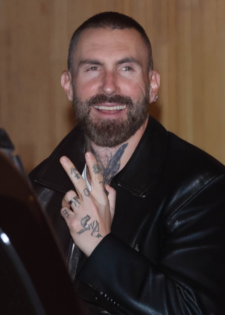 Adam Levine sorri ao atender fãs na saída de hotel em São Paulo