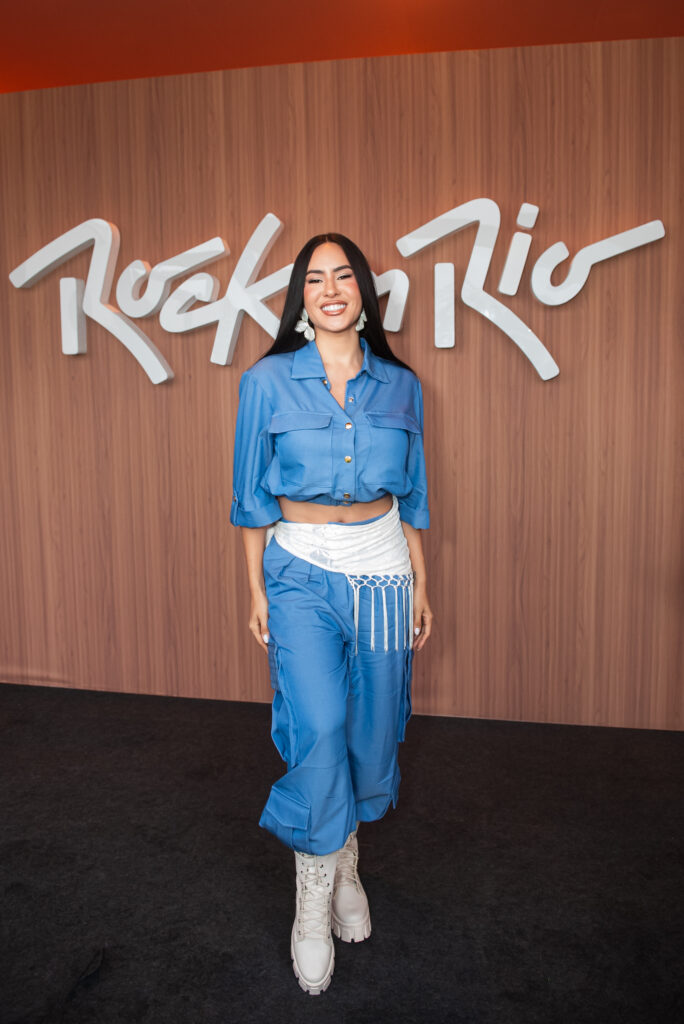Isabelle Nogueira posando diante do painel do Rock in Rio