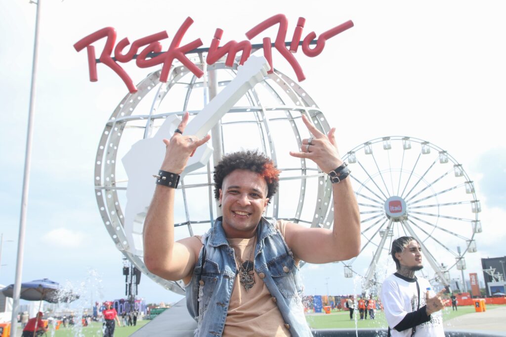 Fã posa diante do símbolo do Rock in Rio na Cidade do Rock